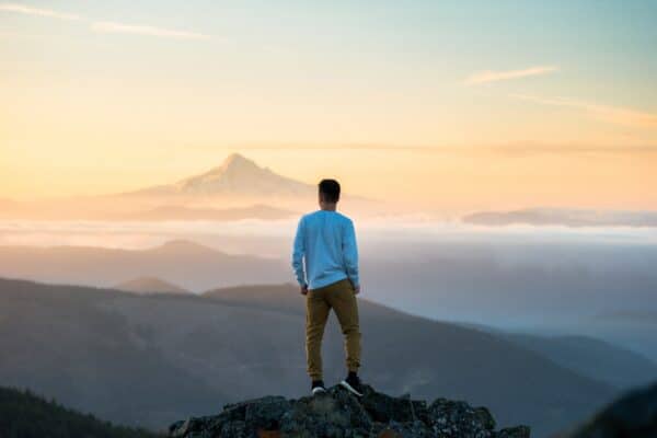 Man looking at the view a sunset from the edge of a cliff
