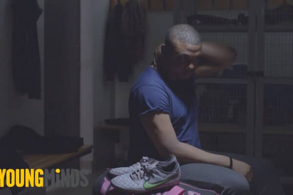 Man sitting on a bench in a locker for Young Minds Video made by Bold Content