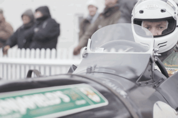 Man wearing a white helmet in a race car