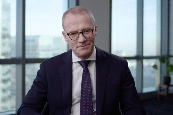 white man with glasses talking to camera in an office with glass windows eLearning