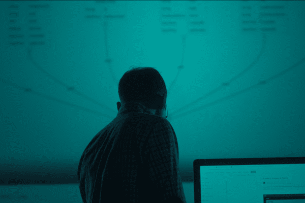 a silhouette of a man stood in front of a projected image of a technical drawing