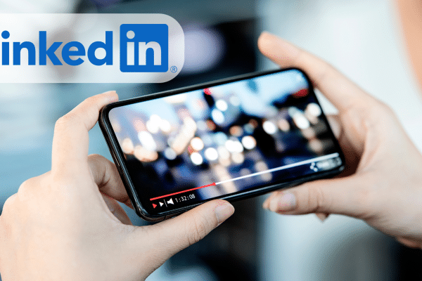 Person holding a phone and watching a video on it, with a linkedin logo in front