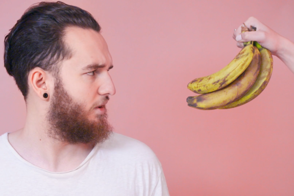 Man looking at bananas on a pink background