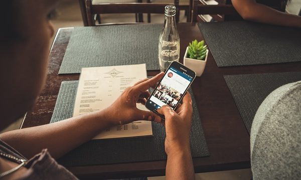Woman scrolling through Instagram at a restaurant table