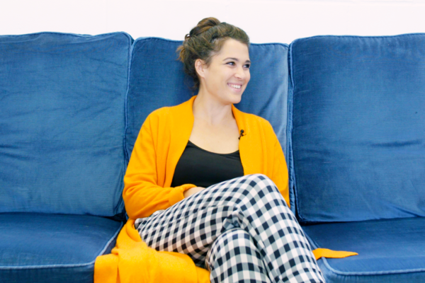 Woman dressed in yellow sitting on a blue couch and smiling