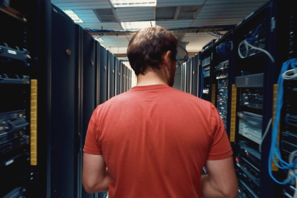 Man in server room with his back to us