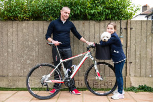 Father and daughter holding a bike and playing with a puppy