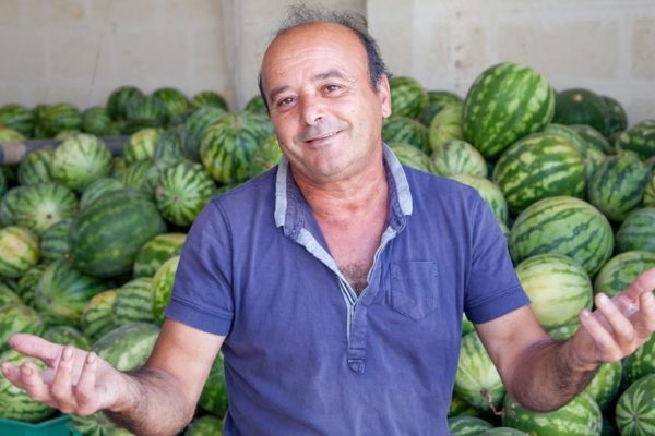Man smiling in front of watermelons