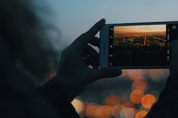 Woman taking a picture of city light on her phone