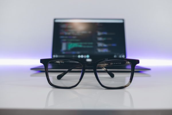 Glasses in front of a laptop which has code on it