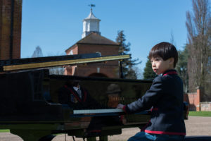 Young child playing the piano in front of a church