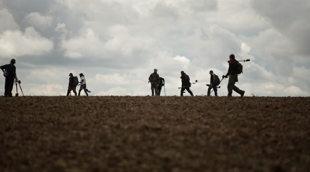 Men using a metal detector in a field
