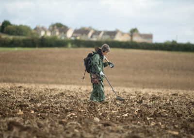 Woman using a metal detector in a field