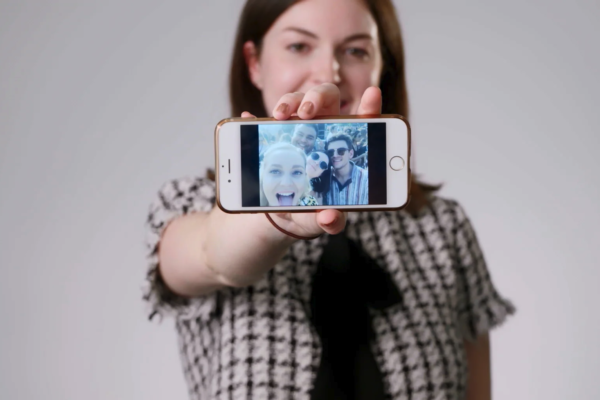 Woman holding a phone to the camera and showing a selfie of her and her friends