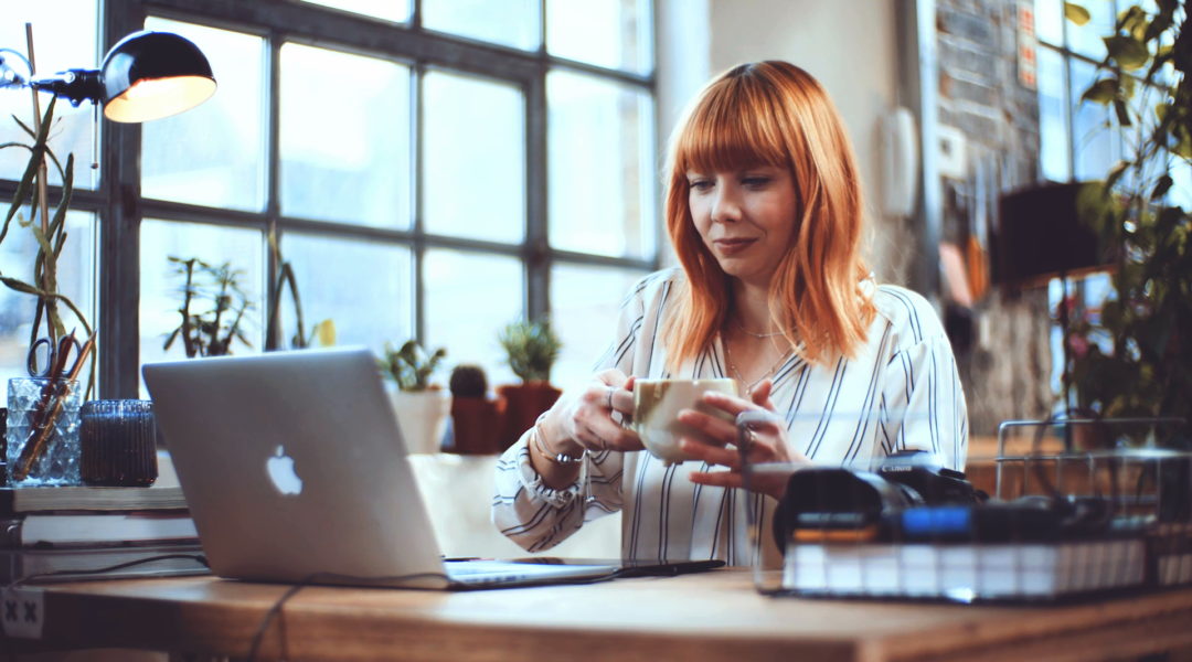 Lady drinking tea looking at laptop