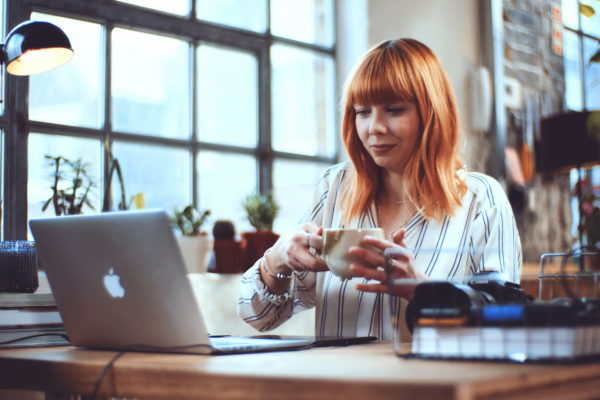 Lady drinking tea looking at laptop
