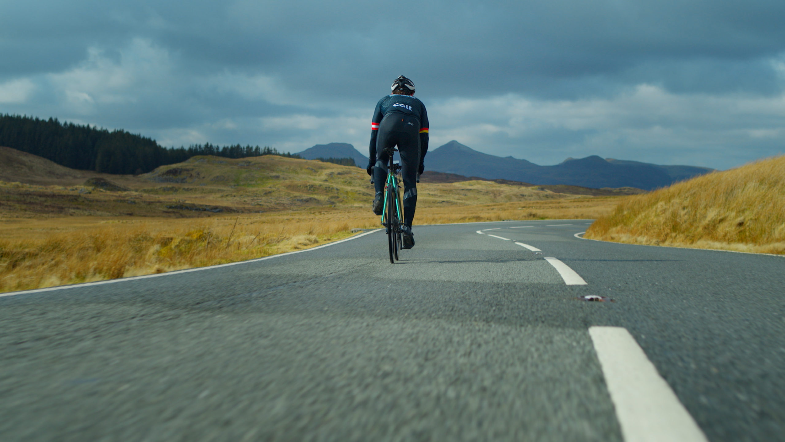 the back of a man cycling on an empty road