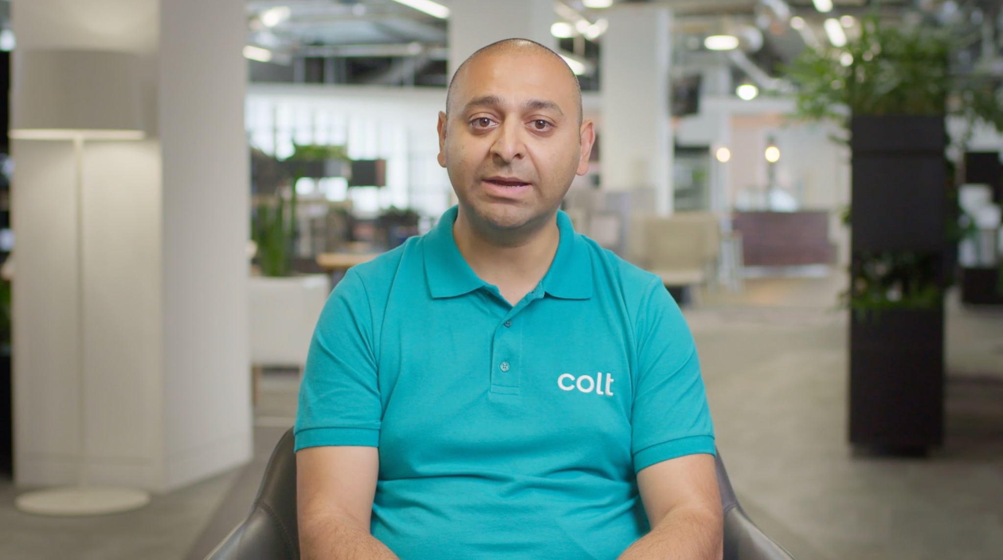 a photograph of a man in a blue tshirt with the logo for tech company Colt