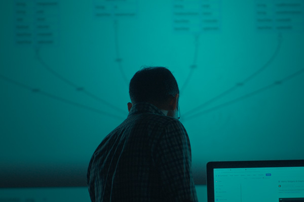 man silhouetted against a project screen with data on