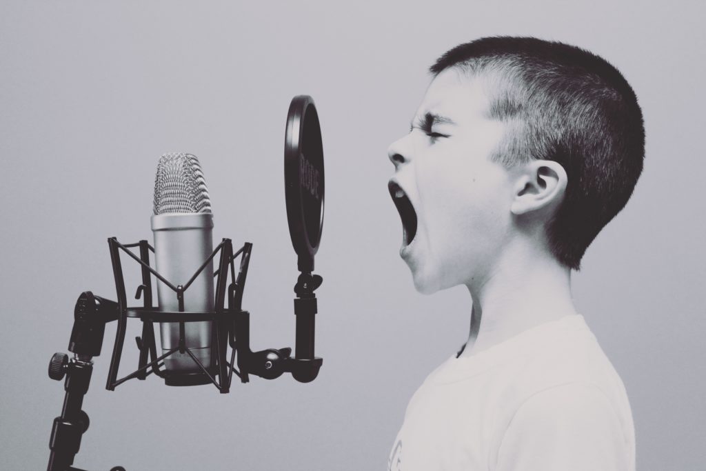 A picture of a young boy screaming into a microphone